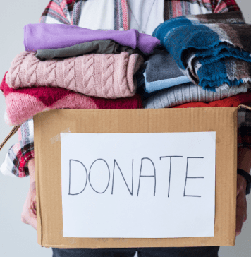 box piled with donations of used clothing