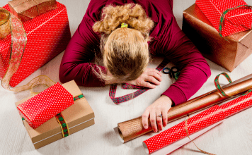 mom laying on top of holiday wrapping paper