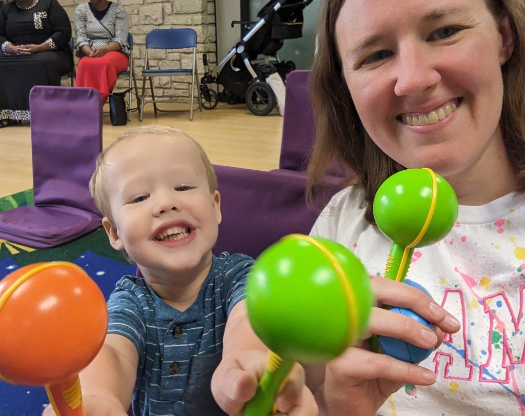 Mother and son smiling and holding shakers for music time at storytime