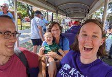 Three adults and one toddler ride a small train