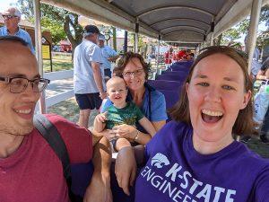 Three adults and one toddler ride a small train