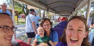 Three adults and one toddler ride a small train