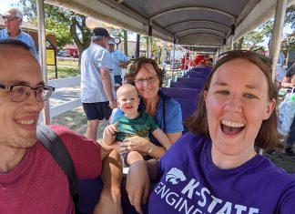 Three adults and one toddler ride a small train