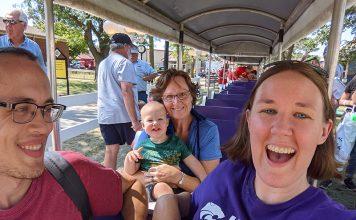 Three adults and one toddler ride a small train