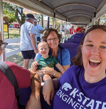 Three adults and one toddler ride a small train