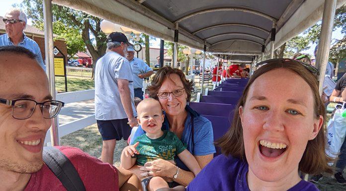 Three adults and one toddler ride a small train