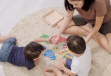 mom and 2 young children playing a game on the floor